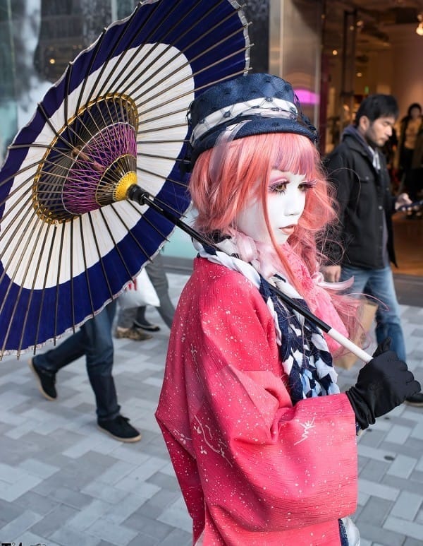 Japanese girl dressed in quirky trendy fashion clothes holding an umbrella in Harajuku