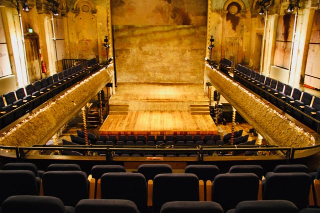 Wilton’s Music Hall in London, UK, featuring a vintage theater with ornate balconies, warm lighting, and an aged wooden stage