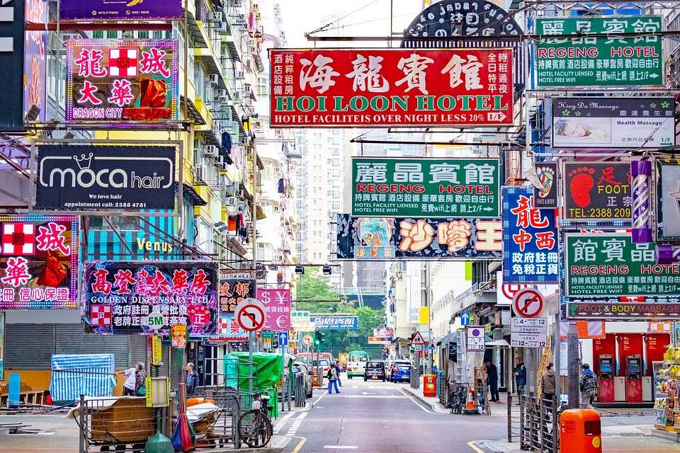 A street with tons of very bright and multi colored signs for the businesses advertising from these buildings. 