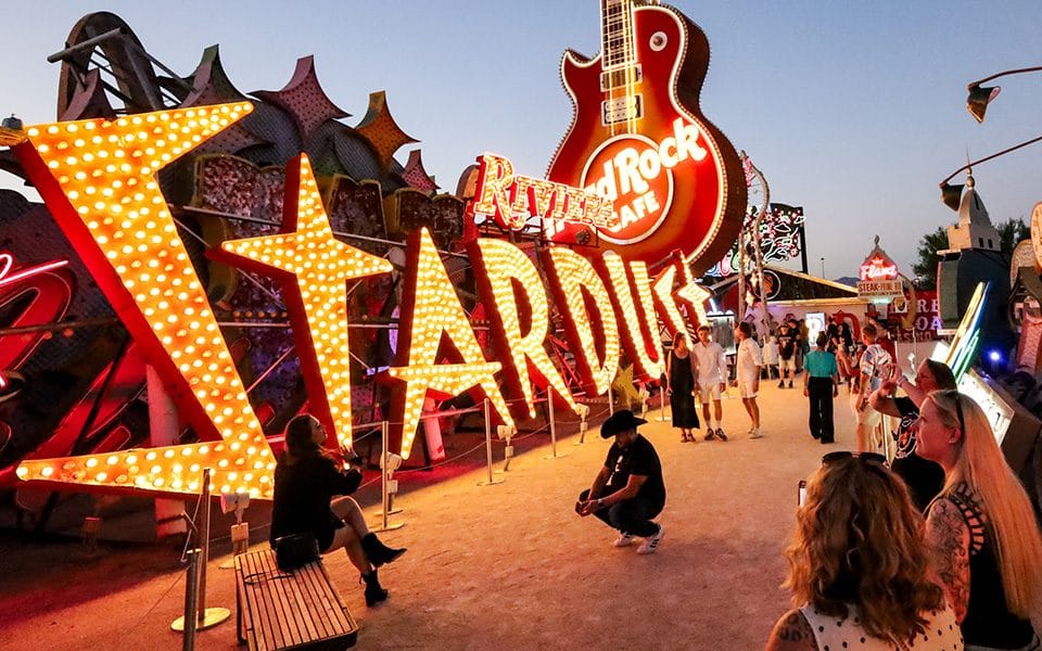 People looking at the Stardust and Hardrock signs lit up at the Neon Museum in Las Vegas. 