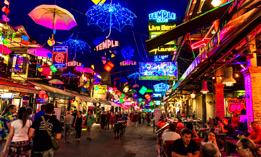 Bright neon lights up and down a street advertising their bars with tons of travelers out enjoying the nightlife of Pub Street in Siem Reap.