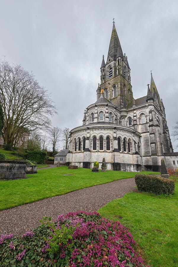 Well groomed grass with a gravel sidewalk leading up to a cathedral that appears to be a few hundred years old. 