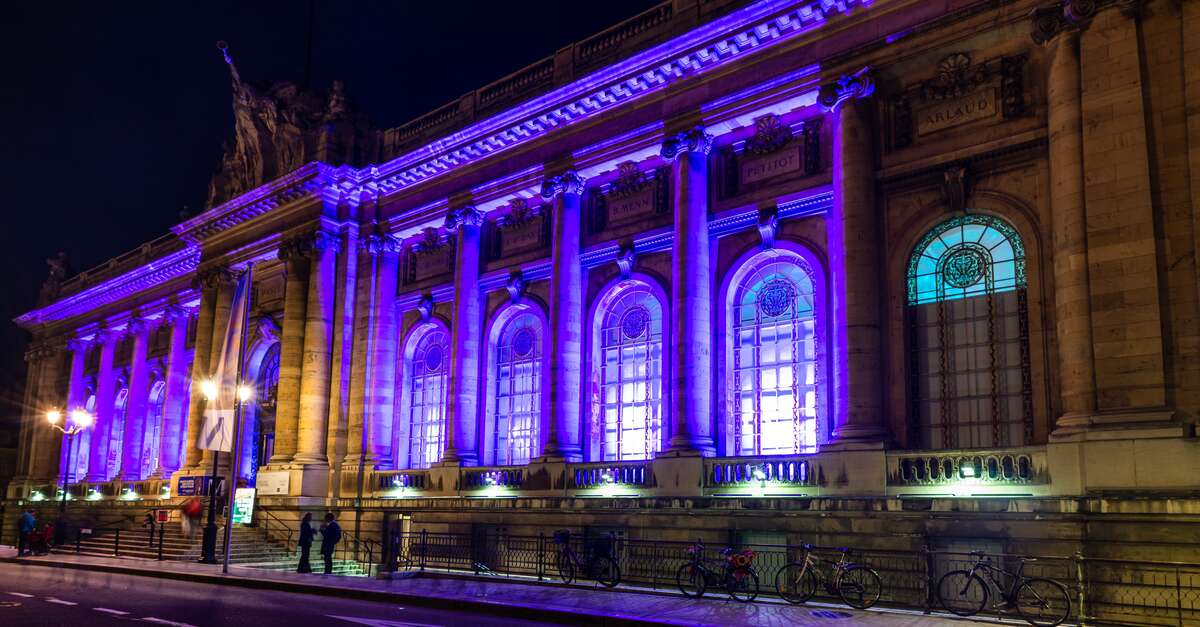 The Museum of Art and History in Geneva, Switzerland lit up with purple lights at night.