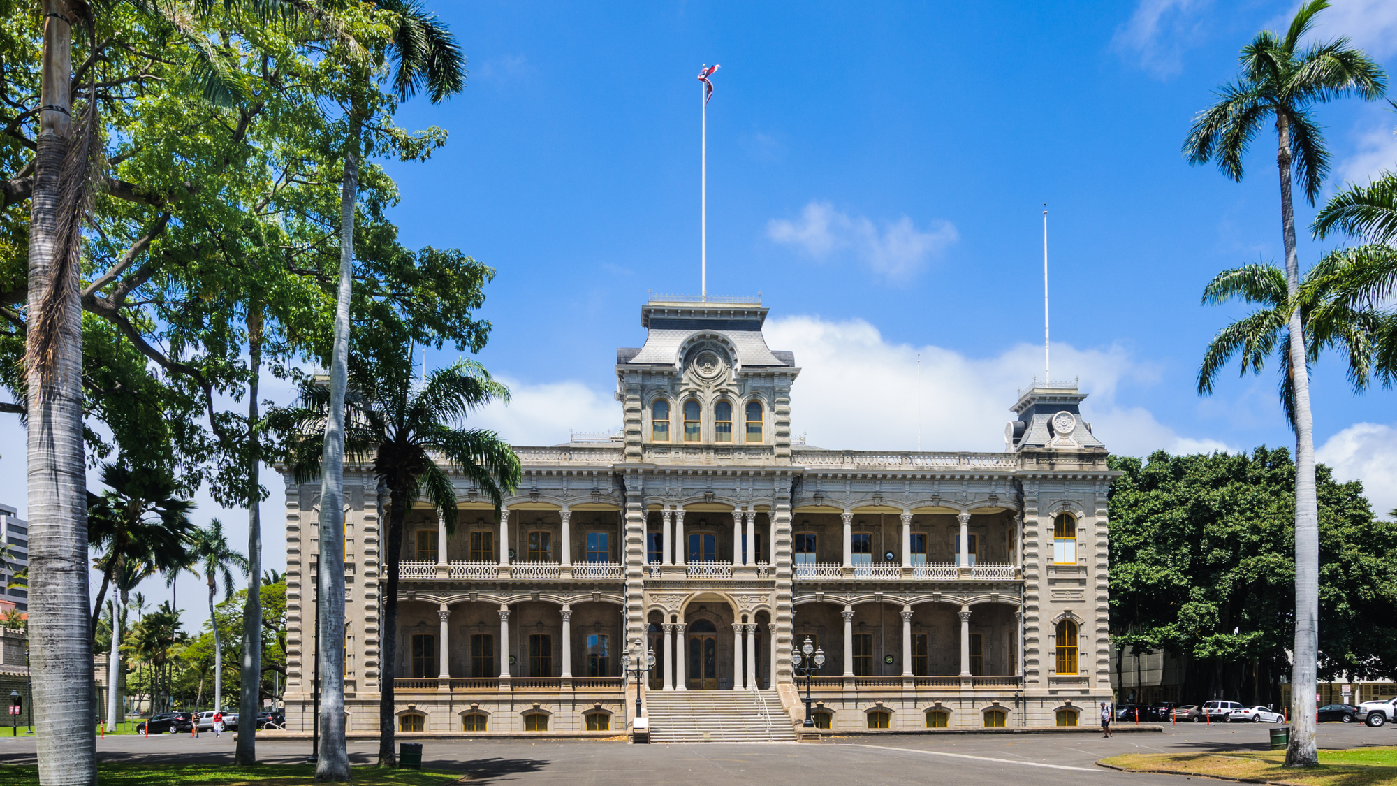 Two story old building surrounded by palm trees and well groomed grass.