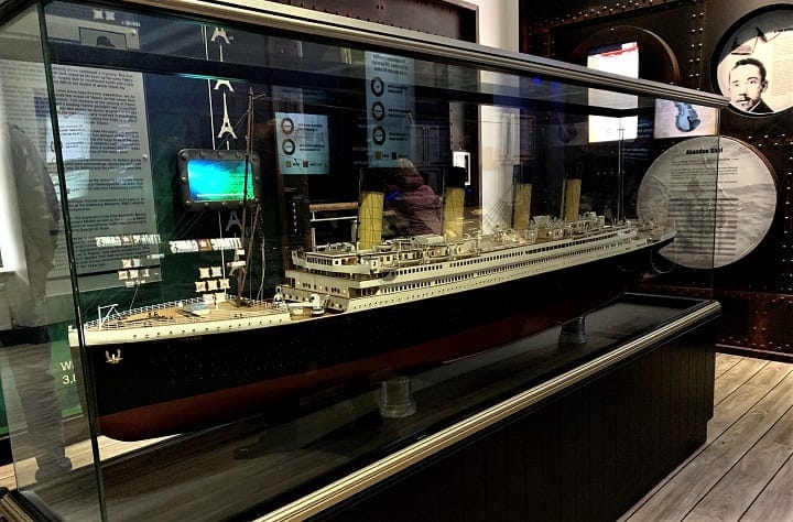 A glass case containing a life like replica of the titanic inside of a modern looking museum. 