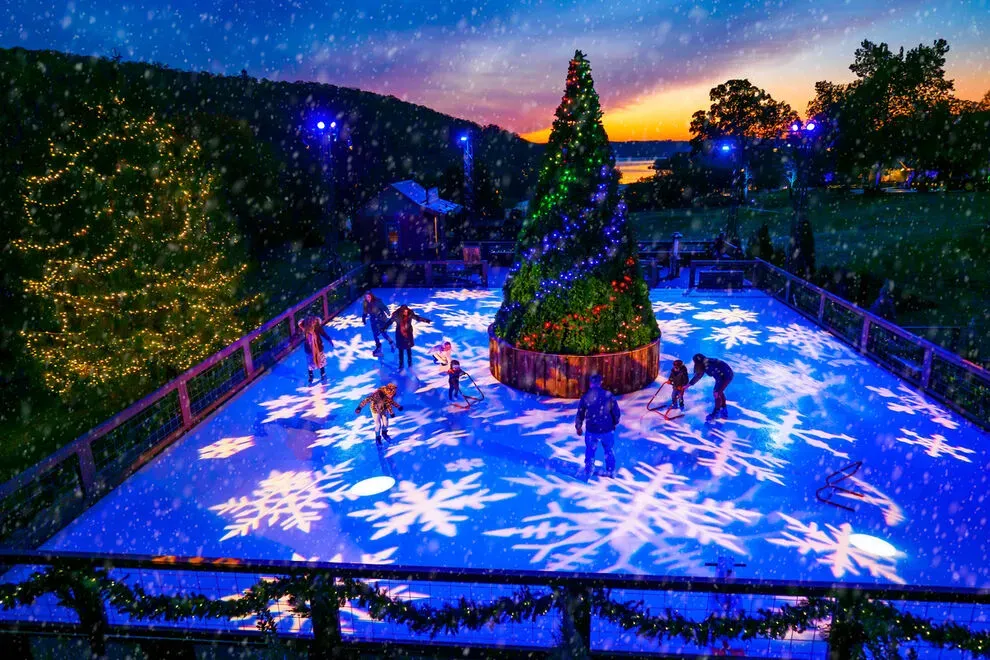 people ice skating at nighttime outdoors with christmas decorations lit up to celebrate Christmas in Branson, Missouri at Big Cedar Lodge