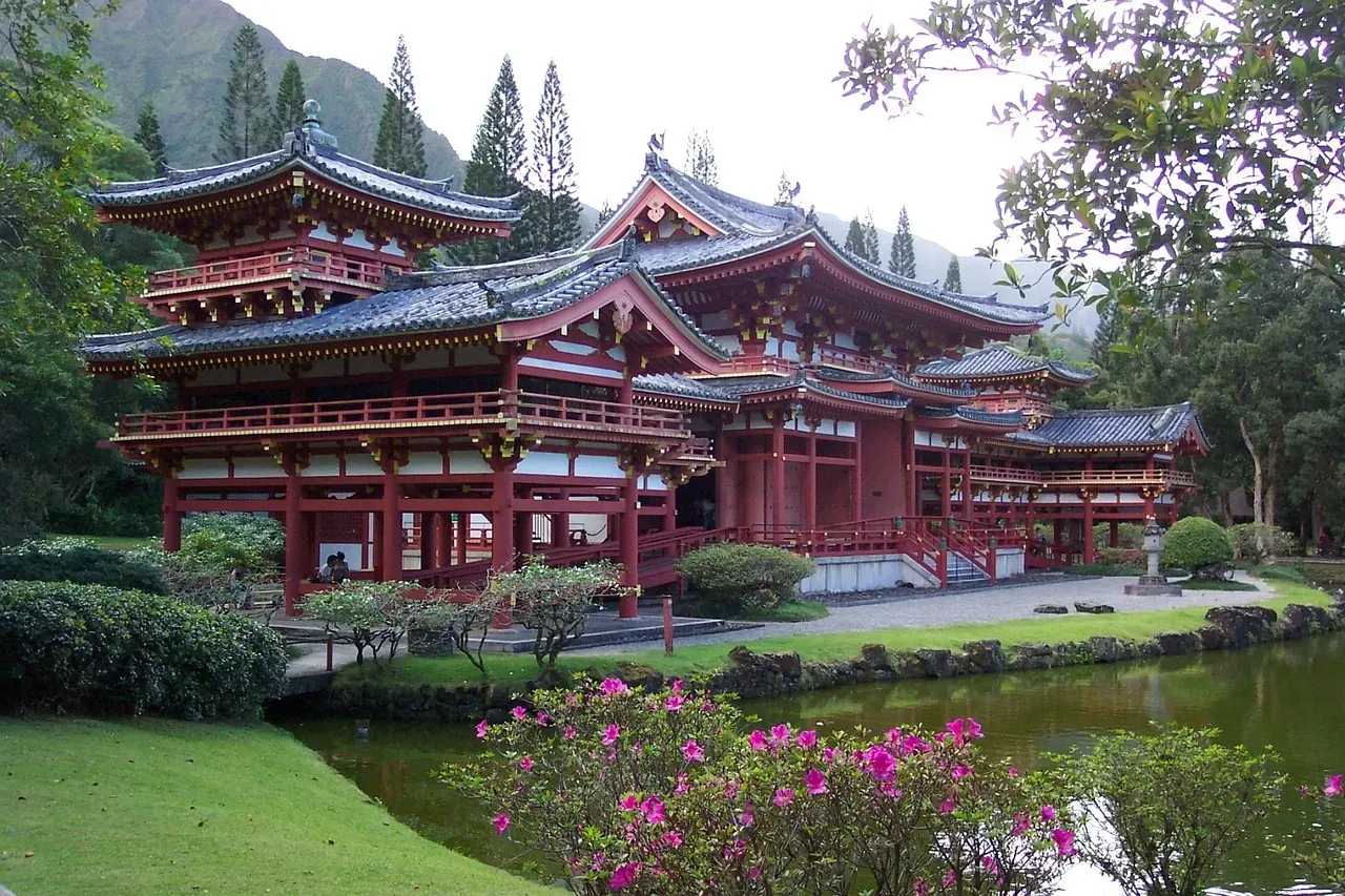 Asian style temple building with well groomed grounds in front of a small pond. 