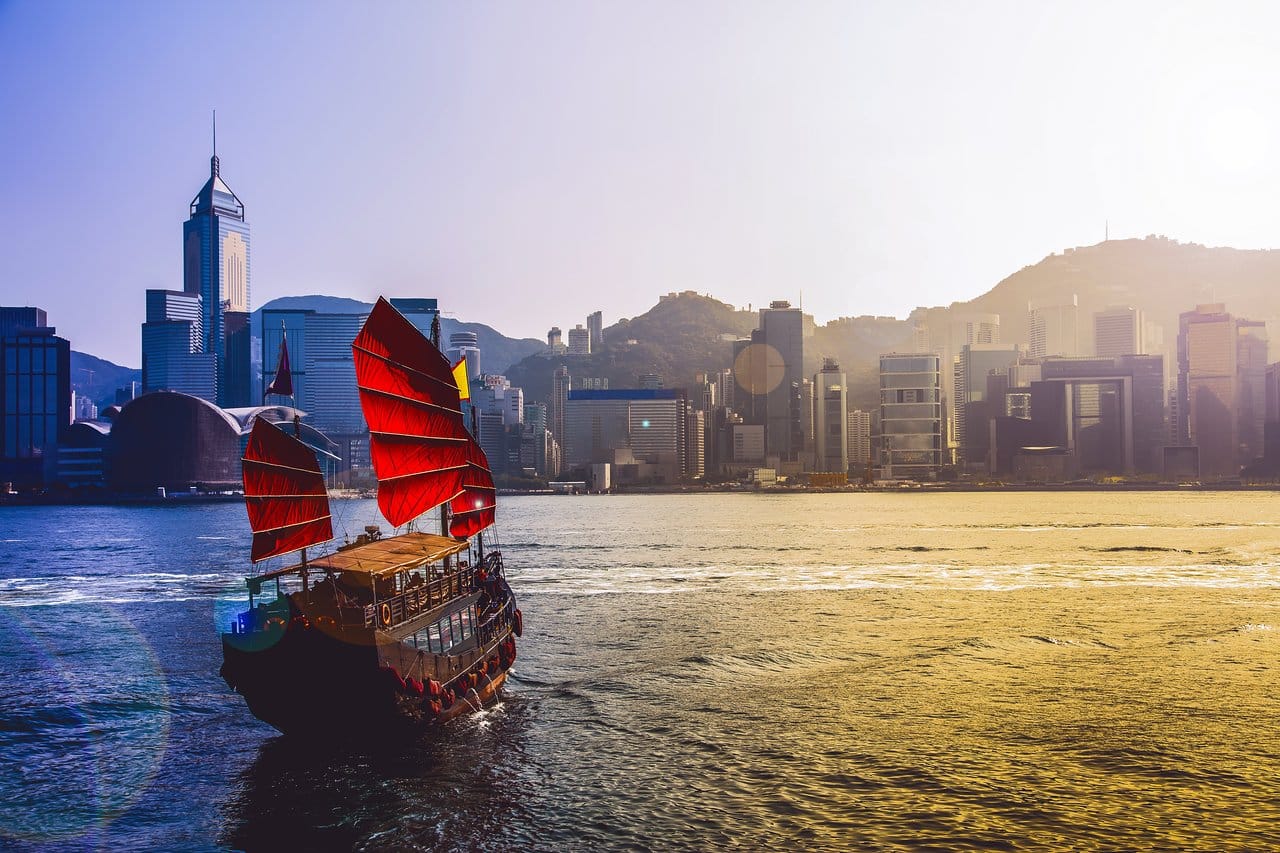 Sailboat crossing the bay in Hong Kong with the skyline on the waters edge in the background. 