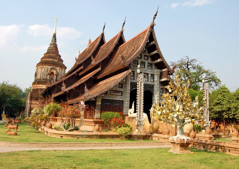 Small chedi temple with the main building having 7 small roofs to create the traditional Thai style with temple with well groomed grounds, and surrounded with green short cut grass. 