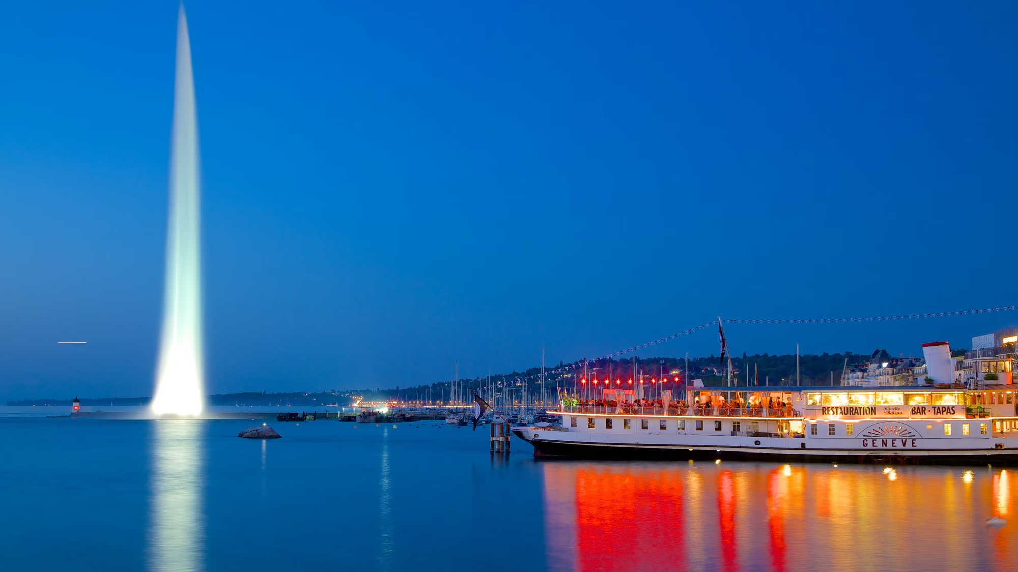 Jet d'Eau is large fountain that shoos very high into the sky and the lights make it appear to be glowing and a popular Lake Geneva attraction. 