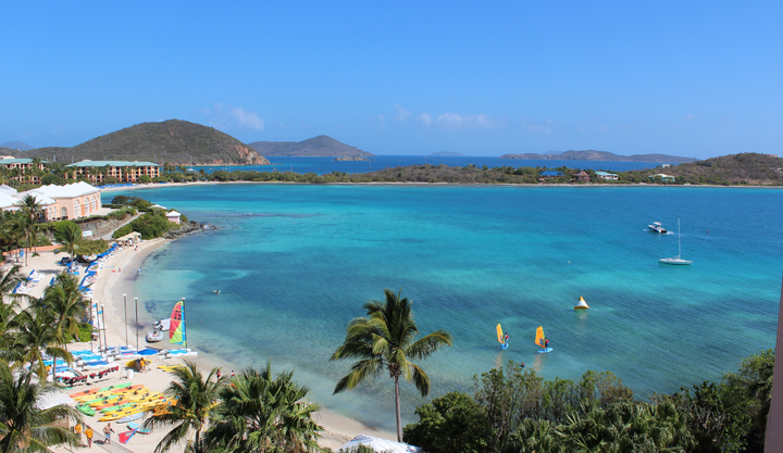 Over looking a white sandy beach and palm trees with a view of the bay in St. Thomas 