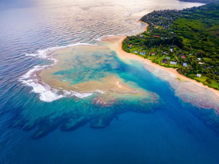 Ariel view of a reef and a beach in Kauai that has a 