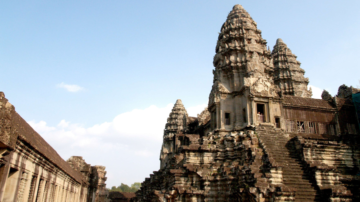 An ancient temple complex covered in intricate carvings with stairs going up the side.